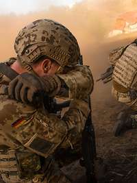 Soldaten im Gefecht. Ein Soldat verdeckt sein Gesicht mit seinem Arm.