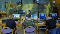 Technikteam Messe Zwei Soldaten und zwei Frauen sitzen vor Video- und Tontechnik
