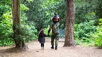 Ein Soldat geht mit zwei Kindern im Wald spazieren.