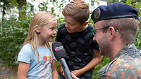 Zwei Kinder sprechen einen Gruß in ein Mikrofon ein.