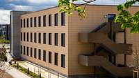 Neubau eines dreigeschossigen Gebäudes mit gelber Fassade und brauner Aussentreppe.