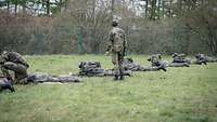 Viele Soldaten liegen im Gras und arbeiten an ihren Waffen.