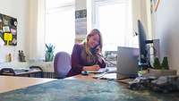 A blonde woman sitting at her desk and making a phone call
