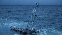 Ein kleines Gerüst mit einem Gittermast schwimmt auf offener See.