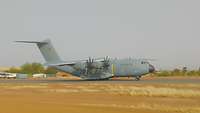 A gray aircraft on a runway in the desert