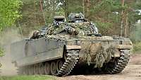 Ein niederländischer Schützenpanzer fährt an der Waldkante durch den Sand.