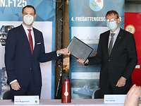 Handover of the ARGE F125 “Sachsen-Anhalt” acceptance protocol to WTD 71 Two men handing over a leather folder