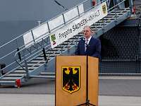 Fregatte Sachsen-Anhalt Rainer Haselhoff Mann im Jacket steht hinter einem Rednerpult. Im Hintergrund eine Stelling mit dem Schriftzug Fregatte „Sachsen-Anhalt“.