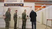 Drei Soldaten stehen neben einem Patienten, der an der letzten Station auscheckt
