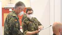 Generalarzt und Stabsarzt schauen sich den Aufklärungsbogen für einen Impfling an