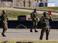 Drei Soldaten in Flecktarnuniform gehen mit großem Abstand über ein gepflastertes Hafenkai.