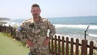 Ein Soldat steht vor einem Zaun, dahinter das Mittelmeer
