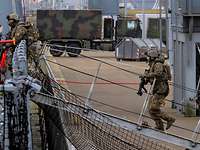 Zwei Soldaten in Flecktarnuniform gehen über eine Stelling an Bord eines Schiffes.