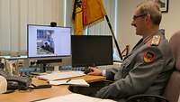 Der Soldat sitzt hinter seinem Schreibtisch und arbeitet an einem Computer.