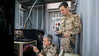 Ein Soldat überprüft ein rotes Kabel. Ein zweiter Soldat steht hinter ihm mit einem Tablet in der Hand