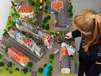 Planübung Brandschutzausbildung Modelltisch Blick von oben auf weibliche Person an einer Modellplattet, auf der sich Modellfahrzeuge und -gebäude befinden.