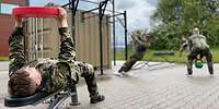 Drei Soldaten trainieren an einem Container, an dessen Außenseite Metallgestelle angebracht sind.