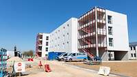 Moderne Unterkünfte Ein dreistöckiges helles Gebäude mit außenliegenden Treppen wird als Unterkunft dienen.