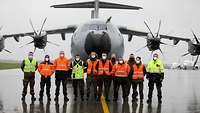 Mehrere Soldaten stehen in Warnwesten vor einem Transportflugzeug A400M