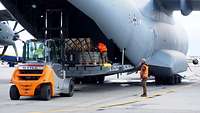 Drei Soldaten stehen auf einer geöffneten Heckrampe eines Flugzeuges