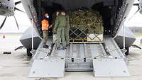 Drei Soldaten stehen auf einer geöffneten Heckrampe eines Flugzeuges