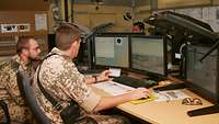 Zwei Soldaten sitzen in einem Büro in Afghanistan und werten am Computer Bild von Aufklärungsmissionen aus.