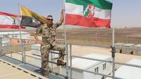 Ein Soldat steht neben einem Fahnenmast, an dem die Landesflagge von Nordrhein-Westfalen weht