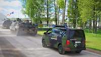 Ein Fahrzeug der Feldjäger folgt zwei Panzern auf einer Straße