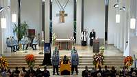 Im Altarraum einer Kirche steht der Sarg des Gefallenen, flankiert von Soldaten in Ausgehuniform.