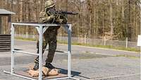 Ein Soldat steht an einem Gestell mit Maschinengewehr.