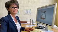 Eine Mitarbeiterin der Lehrmittelwerkstatt sitzt am PC und plant ein Objekt.