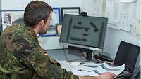 Ein Soldat sitzt vor einem Bildschirm und plant ein Modell für die nächste Ausbildung.