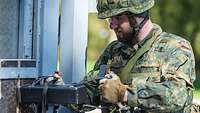 Ein Soldat effnet eine Übungstür mit einem schweren Metallblock, welcher als Türöffner verwendet wird.