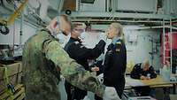 Eine Marinesoldatin und ein Marinesoldat in blauer Arbeitsuniform stehen sich gegenüber.