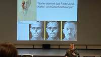 Ein Soldat steht vor einer großen Leinwand, darauf sind Bilder eines Verletzten und seines Heilungsweges.