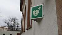 Ein Rettungszeichen außen an der Fassade; zu sehen ist ein Herz mit Blitz darin und ein Kreuz auf grünem Untergrund