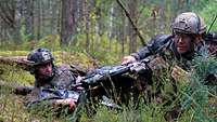 Zwei Soldaten liegen mit ihren Waffen in einem Graben