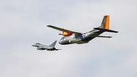 Eine Transall und ein Eurofighter fliegen nebeneinander.