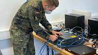Ein Soldat arbeitet an der Verkabelung eines elektronischen Gerätes.