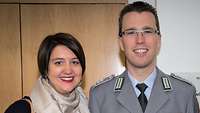 Eine Zivilistin und ein Soldat stehen nebeneinander und schauen freundlich in die Kamera.