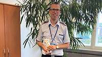 Ein Soldat im Dienstanzug steht vor einer Zimmerpflanze im Büro.