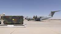 Ein Container steht in der Wüste in Amerika auf einem Flugplatz. Im Hintergrund ist ein A400M.