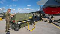 Ein Generator steht an einem Eurofighter, ein Soldat schließt das Kabel an.