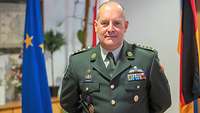 Colonel Muntenaar A soldier is standing in front of two flags