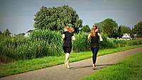 Zwei Frauen joggen durch eine grüne Landschaft. 