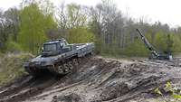 Ein Fahrschulpanzer wird über eine Böschung hinweg mit einem Bergepanzer geborgen.