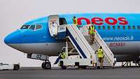 Soldaten mit gelben Warnwesten auf einer Gangway-Treppe an einem hellblauen Boeing-Passagierflugzeug
