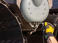 Lösen eines Sicherungsstiftes Eine behandschuhte Hand zieht am Eurofighter neben einem Triebwerk einen Sicherungsstift aus der Öse.