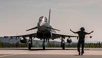 Einweisen in die Parkposition Ein Soldat weist einen Eurofighter in seine Parkposition ein.