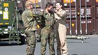 3 Soldaten vor Transportcontainern